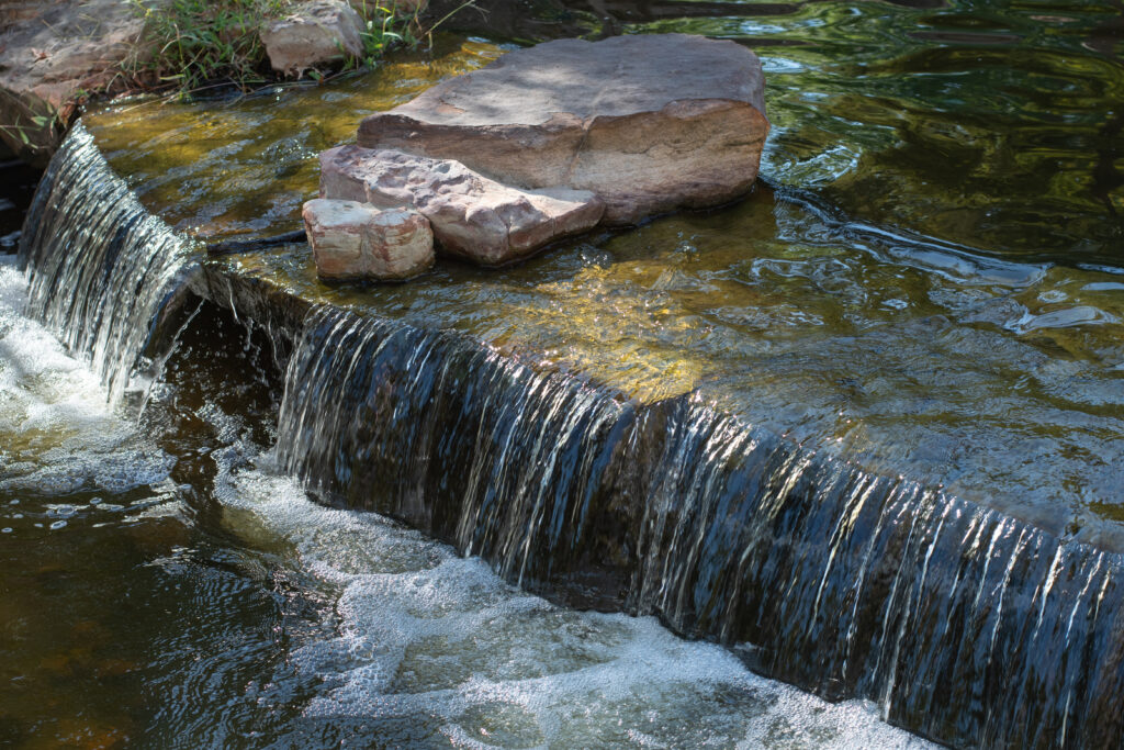 A small waterfall in a large ornamental pond