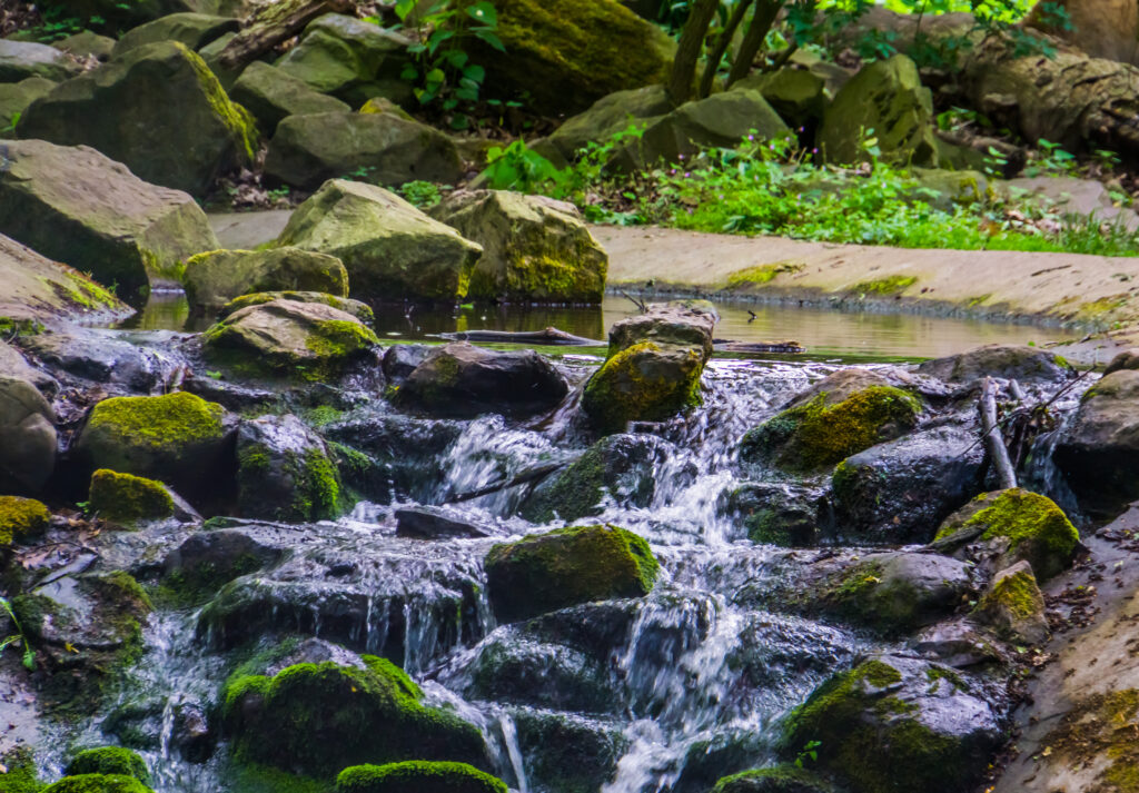 Beautiful waterfall stream with rocks covered in green moss, nature background